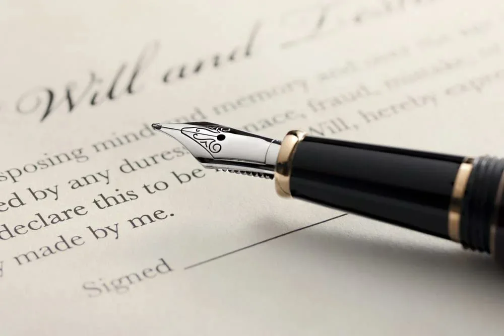A fountain pen resting on a will, above a printed line that reads Signed.