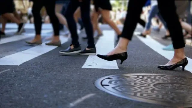 People crossing a city street on foot.